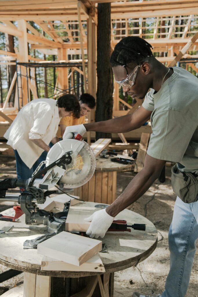 Focused carpenter using a circular saw at an outdoor construction site, cutting wood precisely.